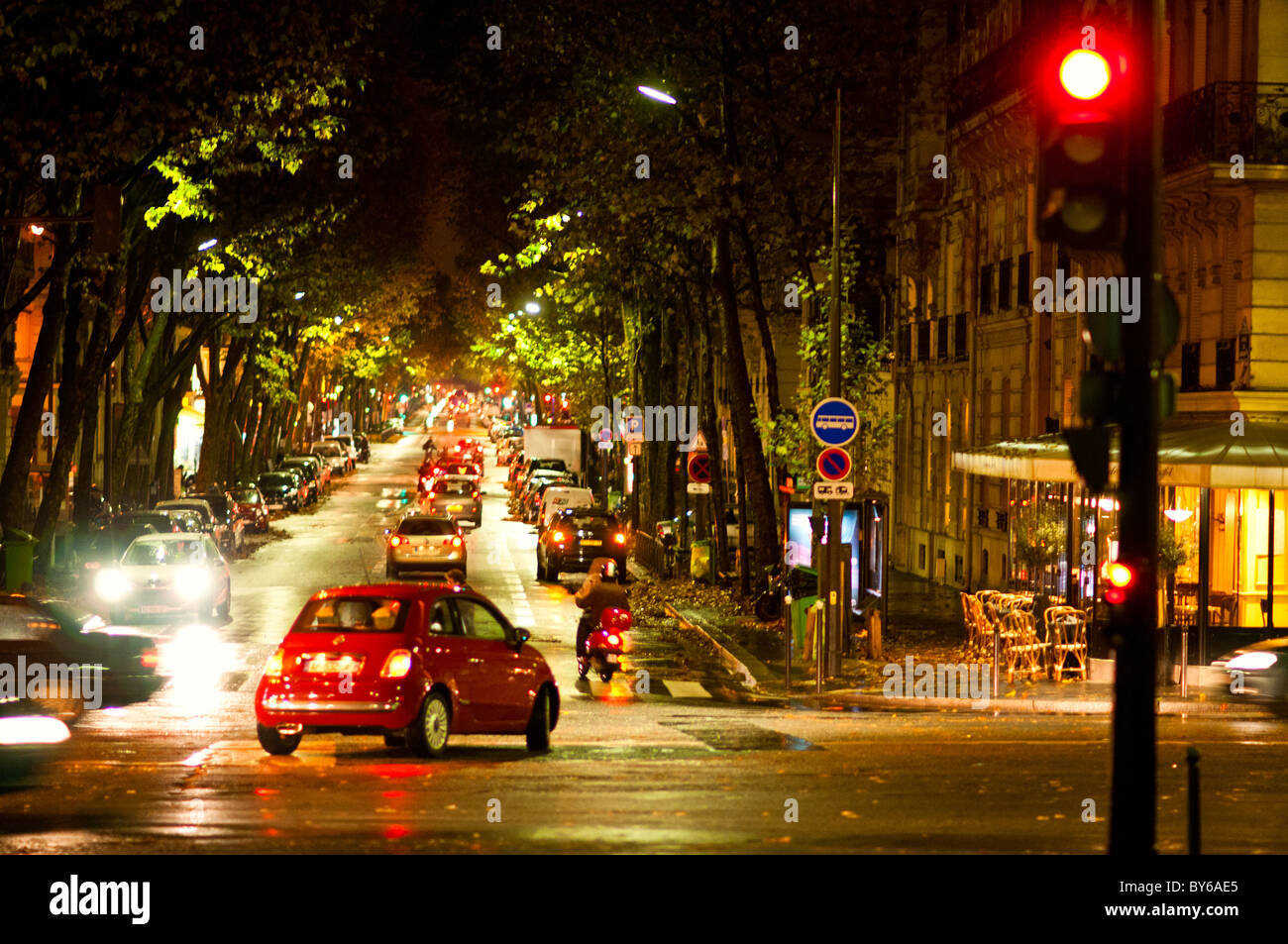 Parigi viale alberato viale bagnato marciapiede traffico Dusk Francia // PARIGI, Francia — le strade bagnate nel 7 ° arrondissement di Parigi sono illuminate al crepuscolo. Un viale alberato presenta veicoli che si muovono lungo la strada e le loro luci si riflettono sul marciapiede umido. Questo crea una luminosa scena urbana, caratteristica dell'atmosfera serale della città. Il quartiere è situato vicino all'iconica Torre Eiffel, un monumento di fama mondiale della capitale francese. Il 7° arrondissement è un'area centrale ed elegante nella regione dell'Ile-de-France, conosciuta per la sua grandiosa architettura e gli edifici governativi. Foto Stock
