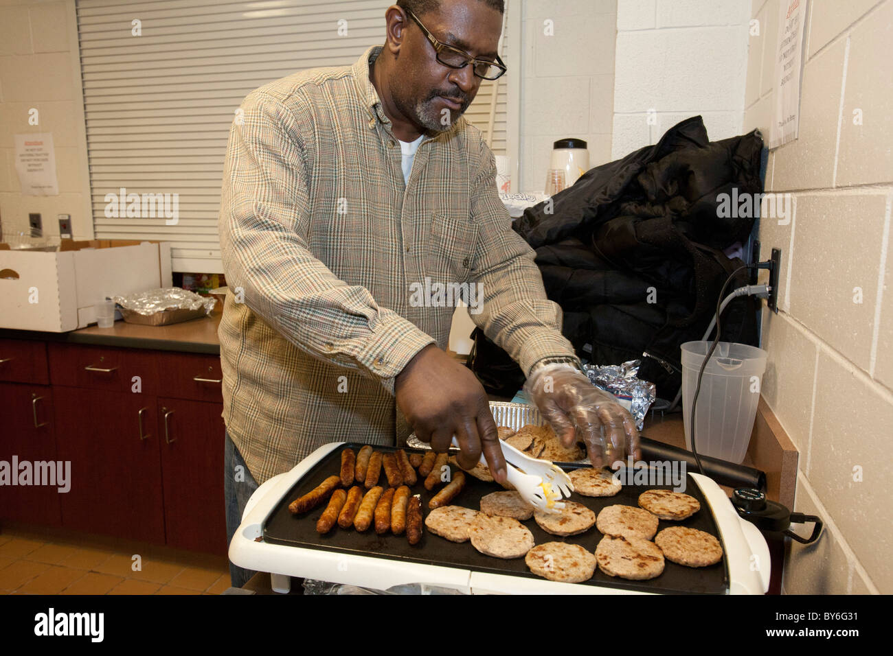 Mount Clemens, Michigan - un volontario cuochi la prima colazione per i senzatetto per il Martin Luther King holiday. Foto Stock