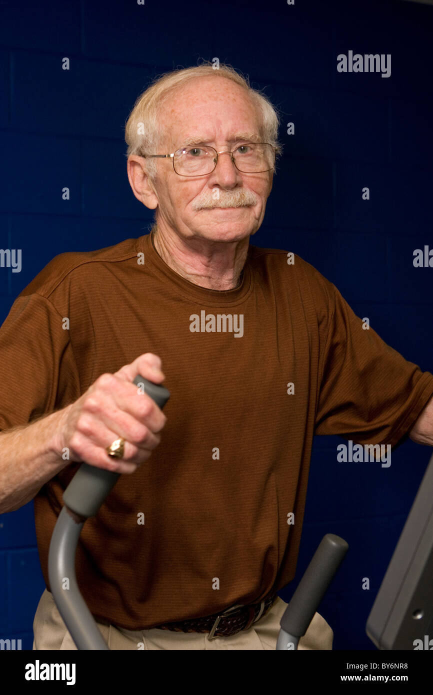 Senior felice l'uomo lavora su una macchina ellittica in palestra. Foto Stock