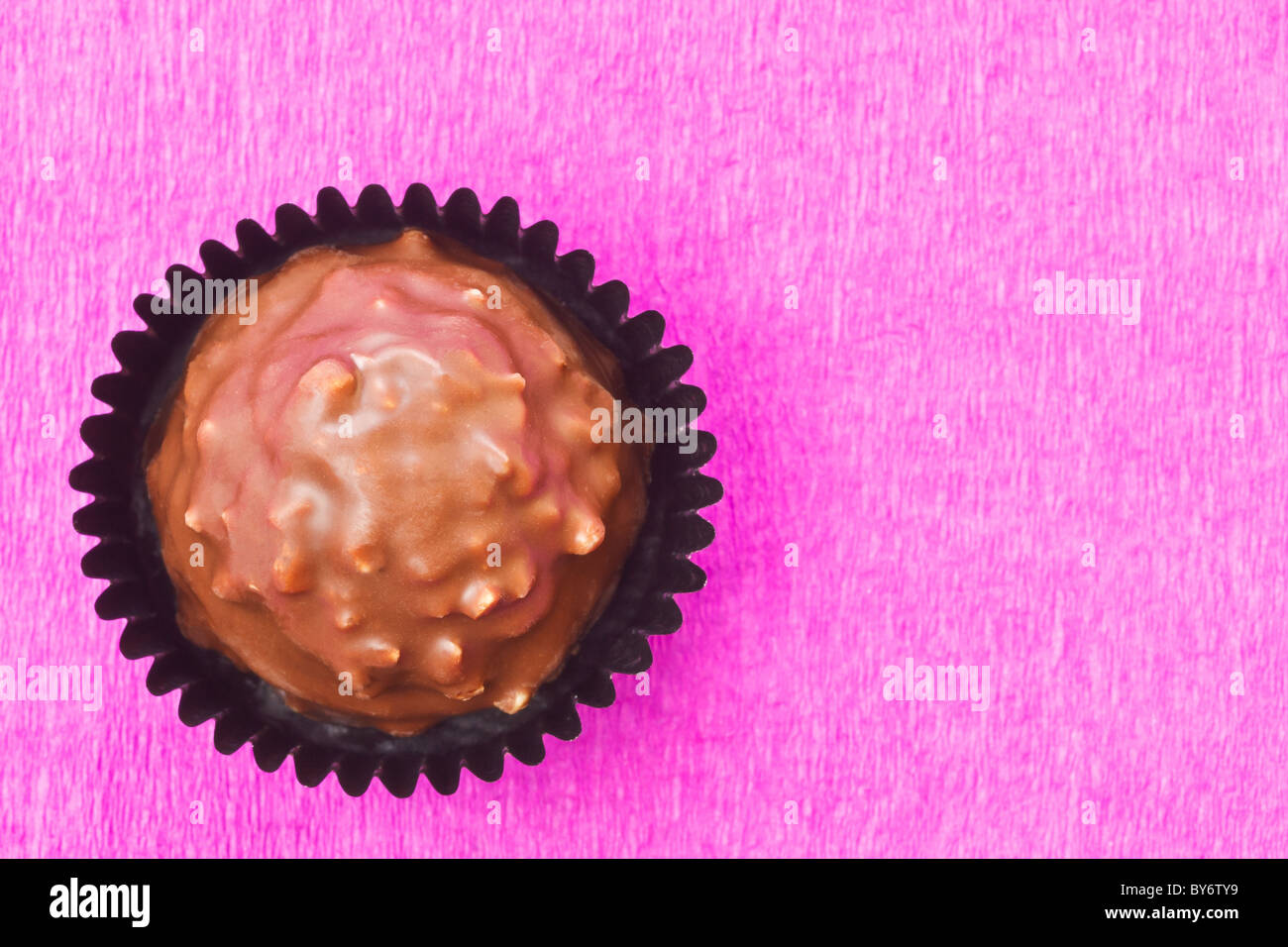 Il cioccolato al latte dolce con scaglie nocciola su sfondo rosa Foto Stock