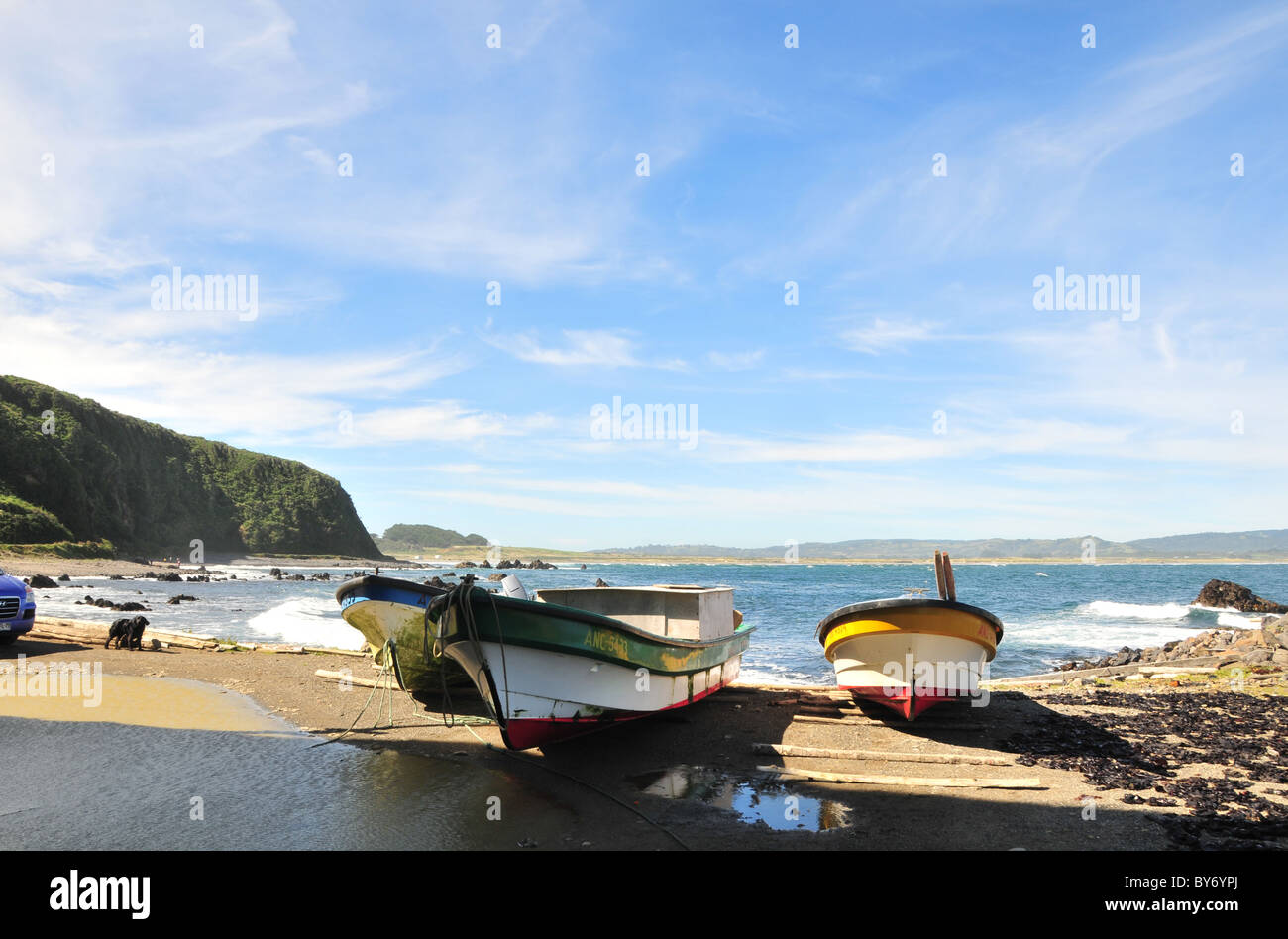 Tre piccole barche da pesca ormeggiate sul log alaggio, lato nord Cocotue Bay, Mar Brava Costa dell'Oceano Pacifico, Isola di Chiloe, Cile Foto Stock