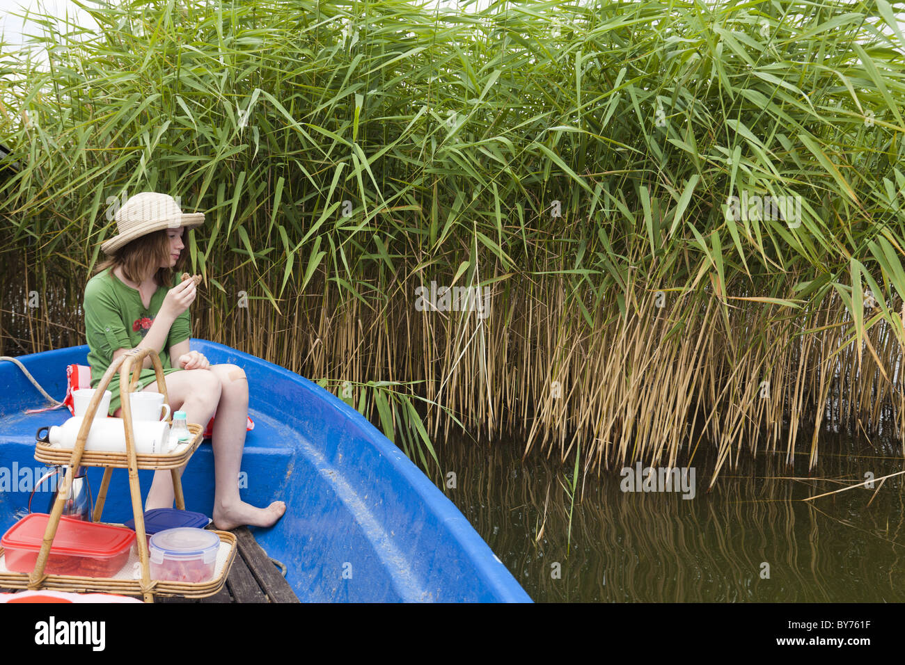 Ragazza che indossa cappello di paglia avente un picnic in una barca sul lago Teupitz, Brandeburgo, Germania Foto Stock