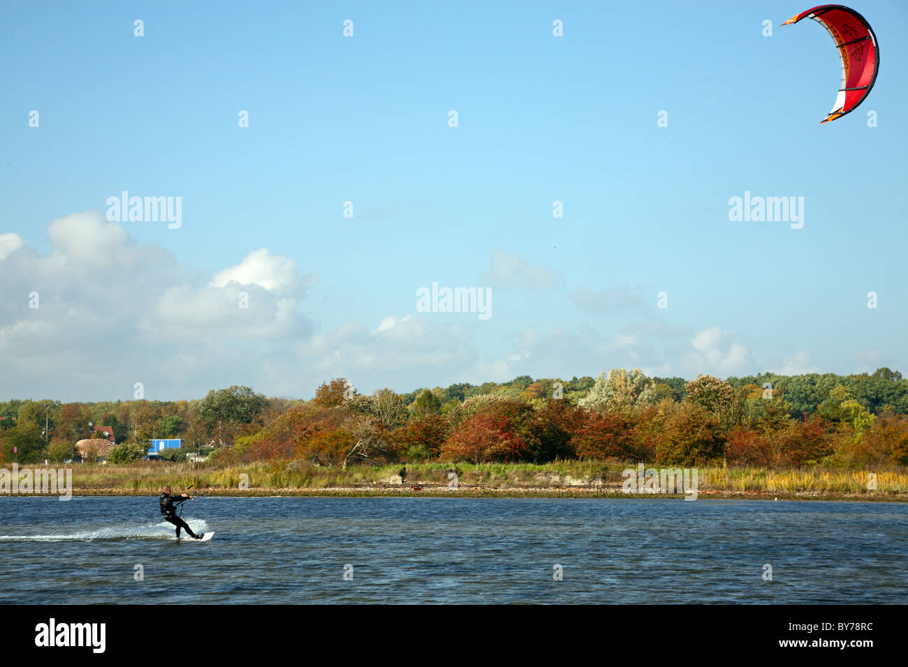 Kitesurfer navigare sul suono vicino alla costa un pomeriggio autunnale Foto Stock