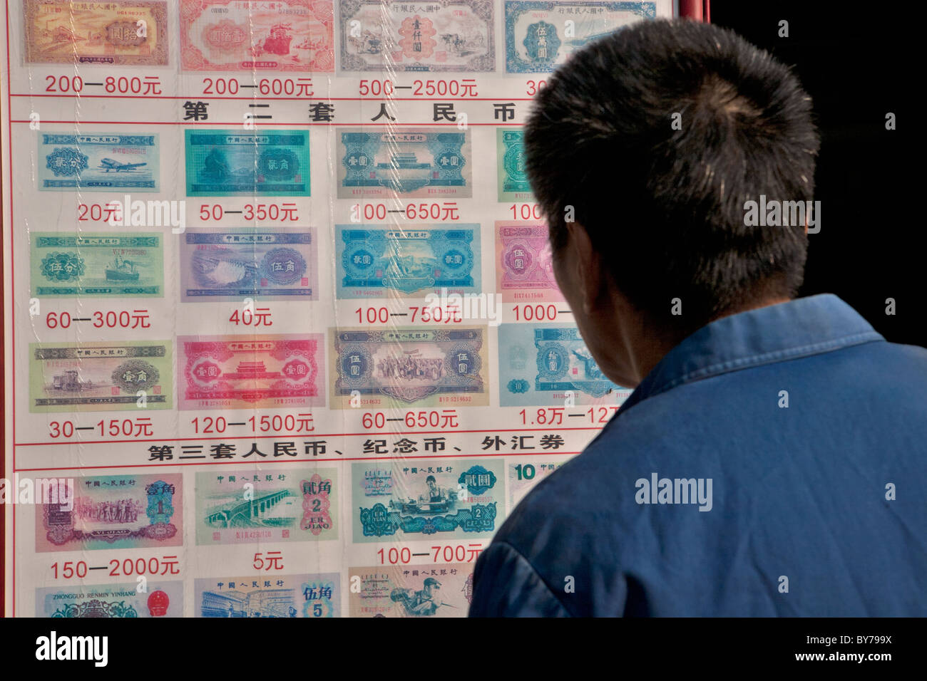 Un uomo guarda il grafico della moneta note, Duolan Road, Shanghai, Cina Foto Stock