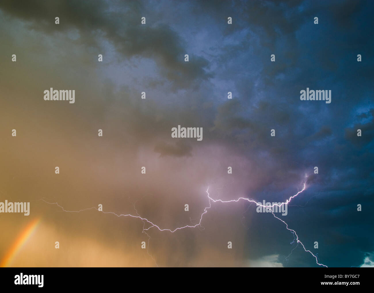 Colpo di fulmine in una tempesta di sera con una parte di un arcobaleno Foto Stock