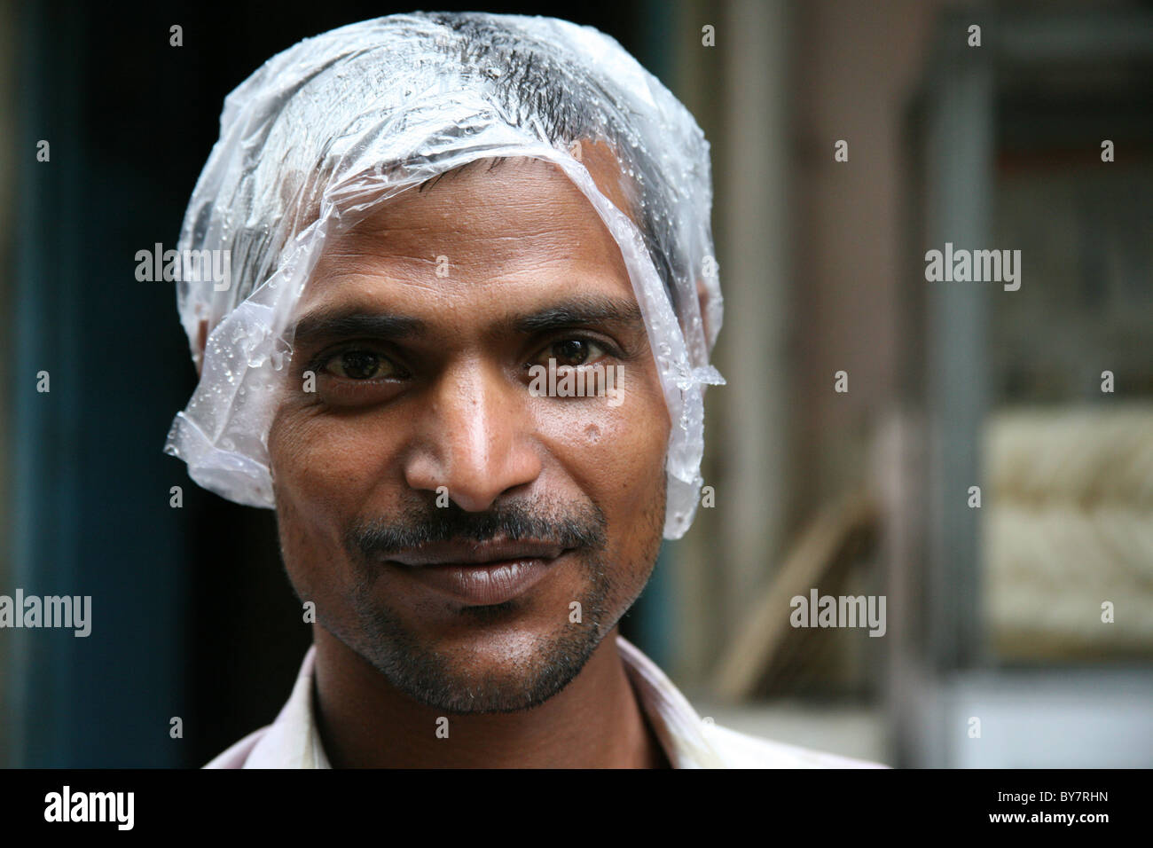 Ritratto di un uomo indiano indossando un improvvisato in sacchetto di plastica hat nella stagione delle piogge monsoniche Foto Stock