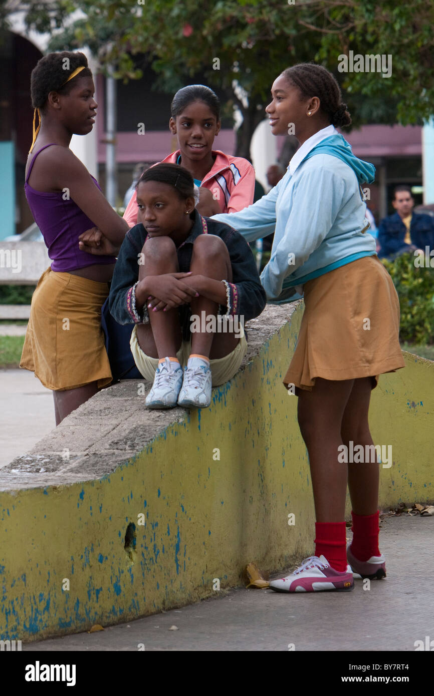 Cuba, La Habana. Afro-cubane ragazze parlano in un parco. Il giallo gonne identificarli come gli studenti della scuola secondaria. Foto Stock