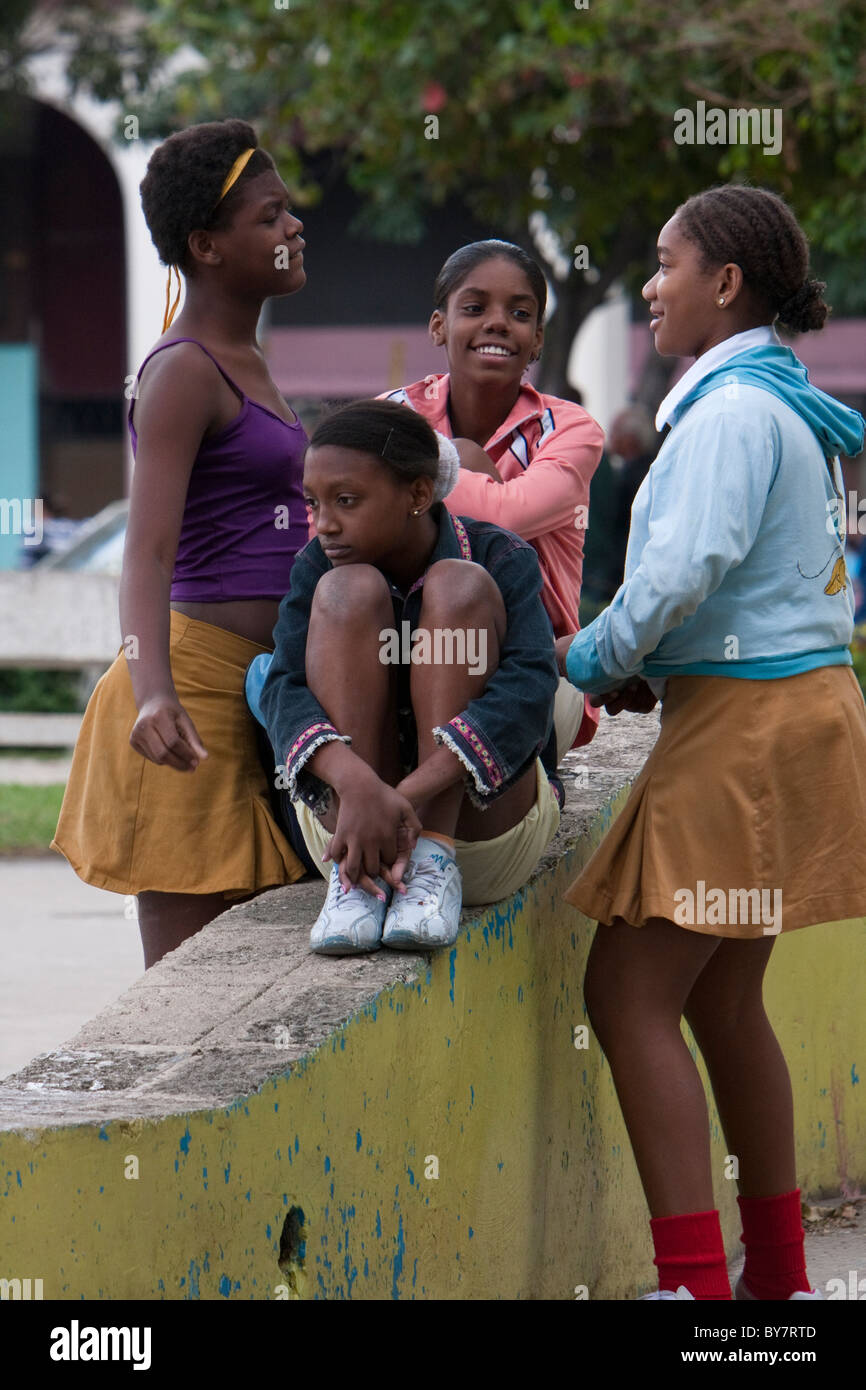 Cuba, La Habana. Afro-cubane ragazze parlano in un parco. Il giallo gonne identificarli come gli studenti della scuola secondaria. Foto Stock