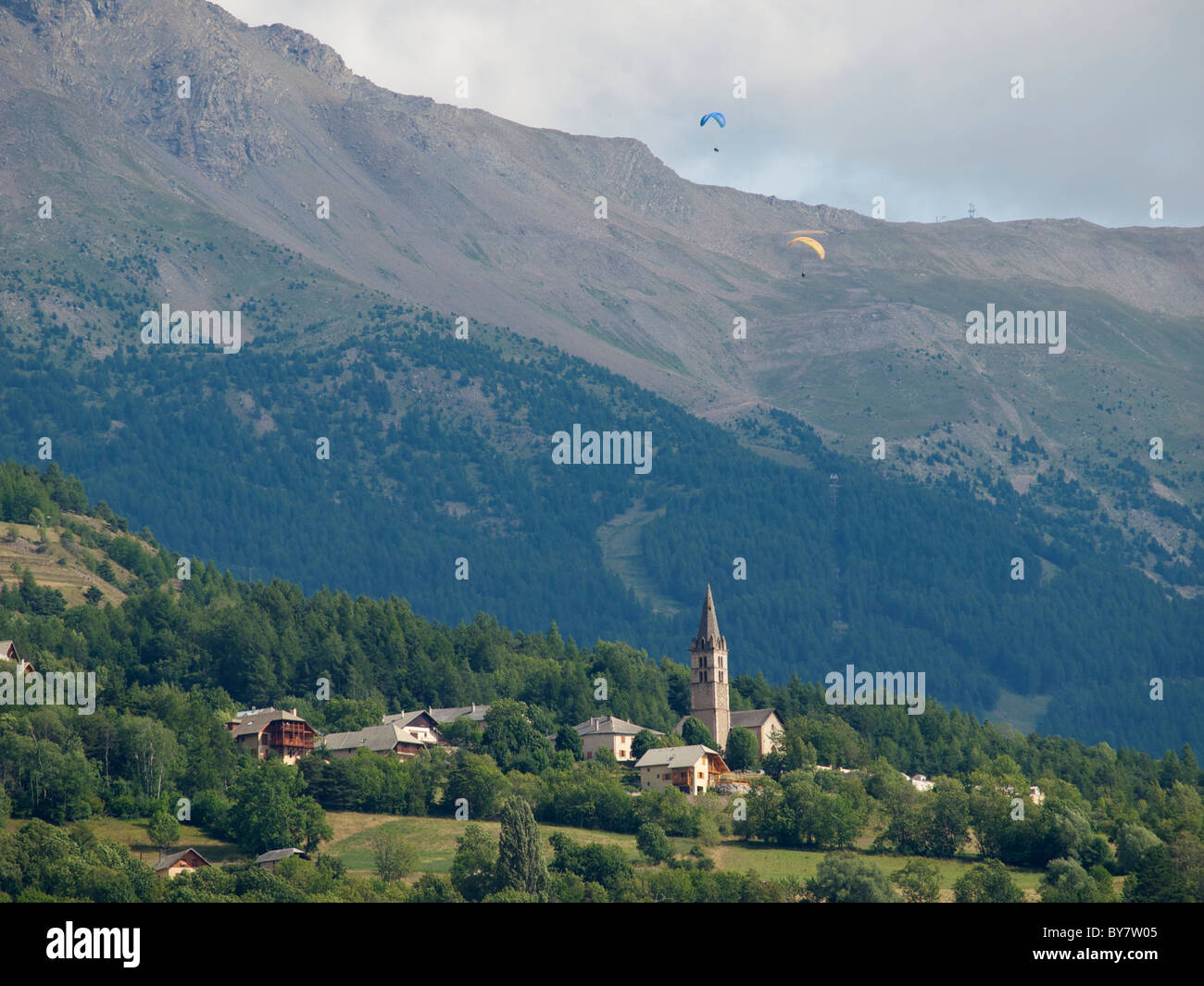 I parapendii sopra un piccolo villaggio nelle Alpi francesi, girato da Embrun, Hautes Alpes, Francia Foto Stock