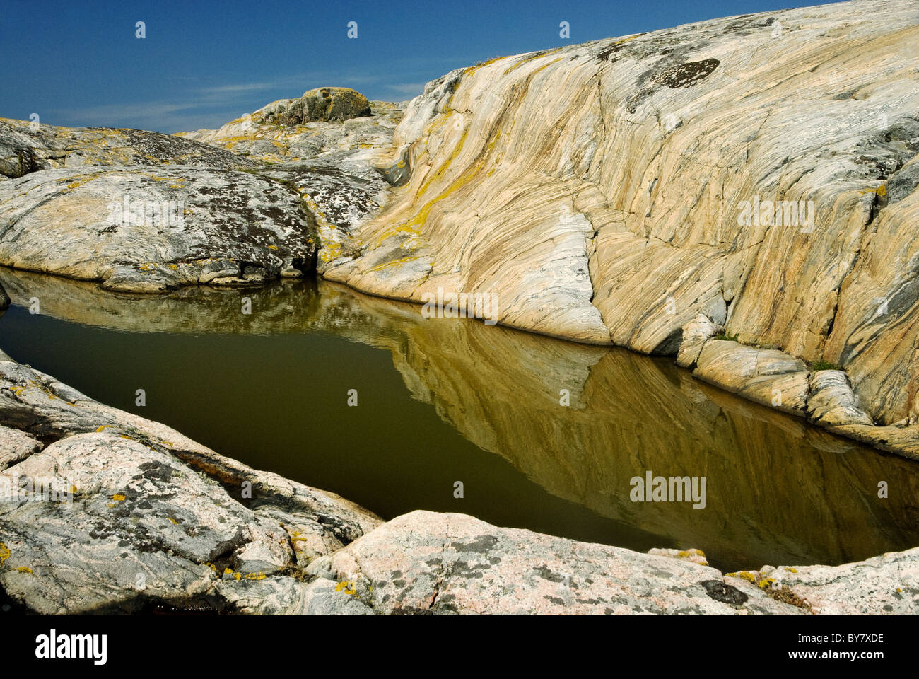 Piscina di acqua piovana su un piccolo glacially-isola a forma di liscio, di granito rosa e gneiss, sulla costa occidentale della Svezia Foto Stock