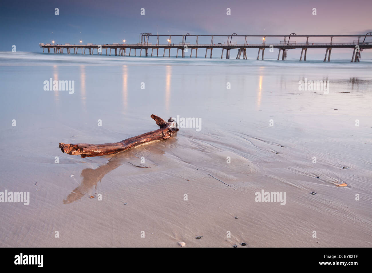 Legno sulla spiaggia con pier in background Foto Stock