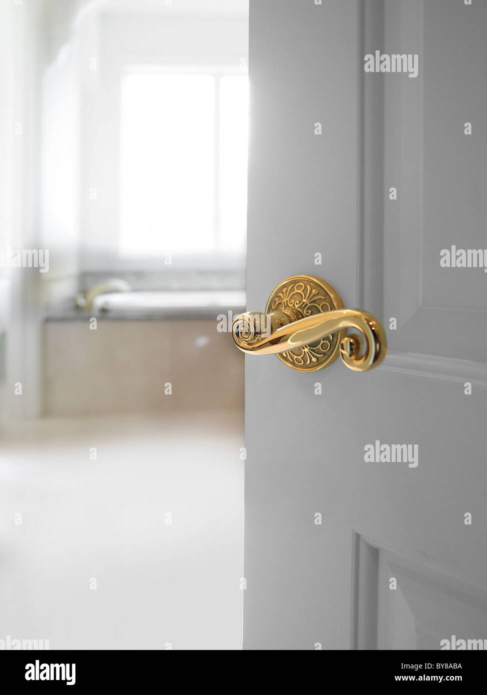 Porta con manopola di fantasia parzialmente aperto con bianco luminoso con bagno in camera Foto Stock