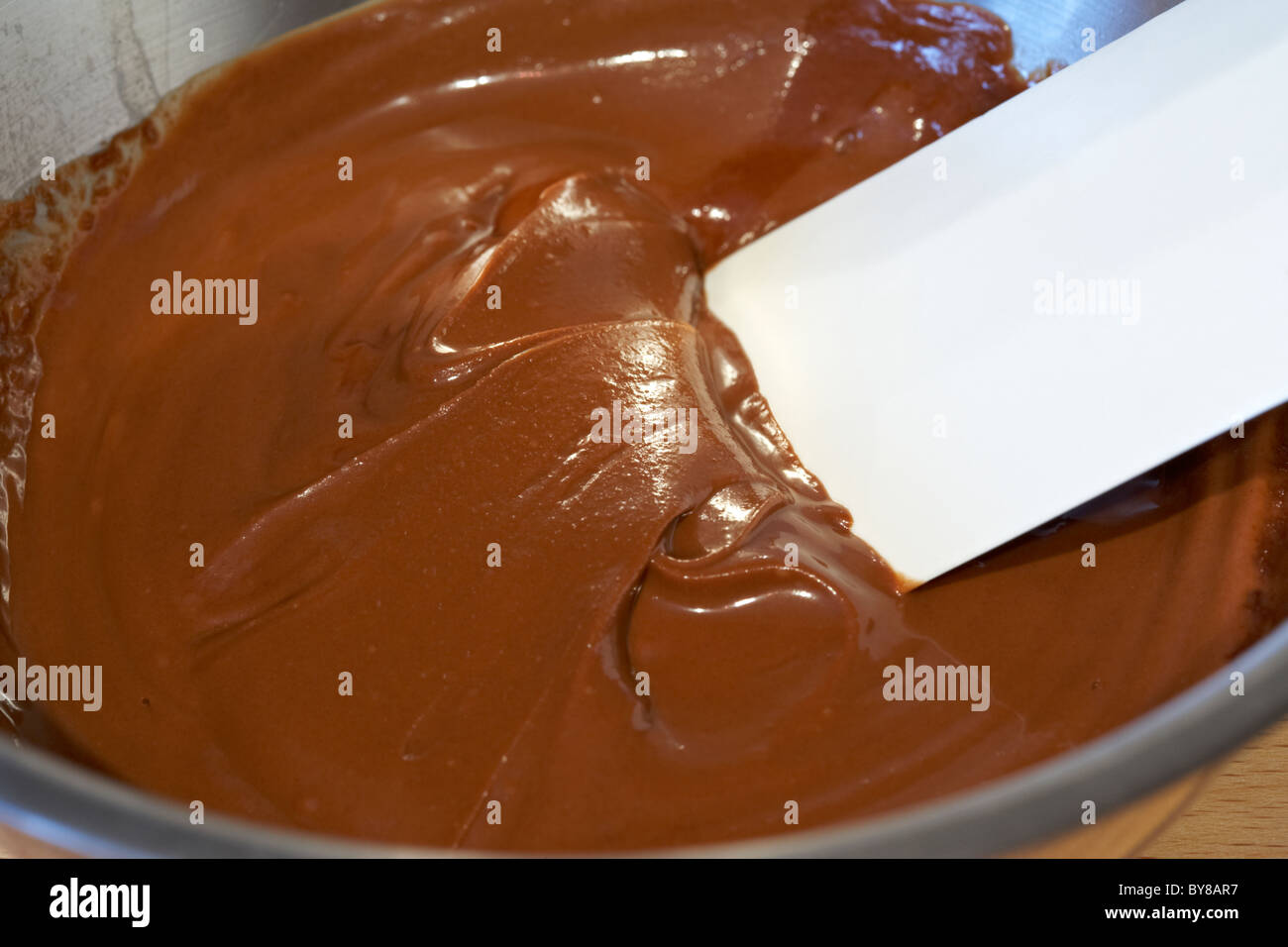 Il cioccolato fuso e la spatola in un metallo della vaschetta di miscelazione per la cottura Foto Stock