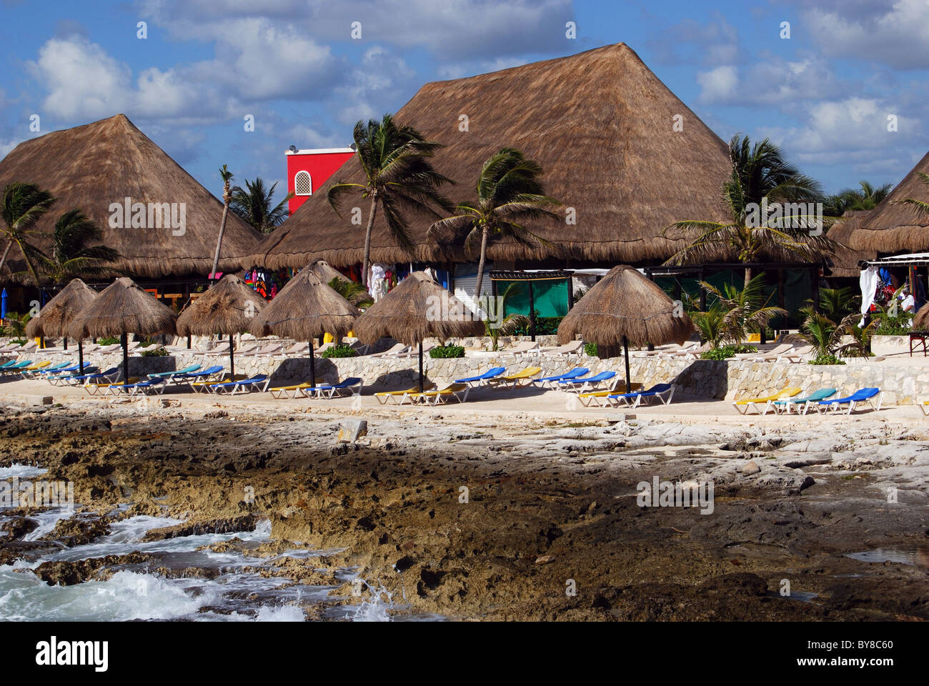 Spiaggia con tetto di paglia di edifici e ombrelloni, Costa Maya, regione sud-orientale, Caraibi, Messico. Foto Stock