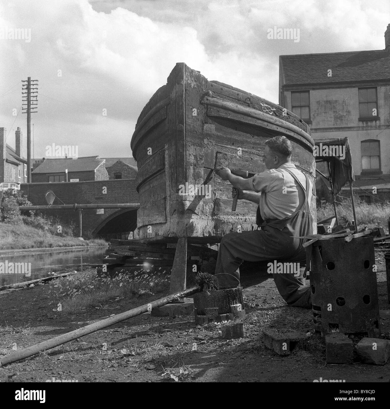 Uomo che ripara narrowboat sul canal area di Wolverhampton 1960 Foto Stock