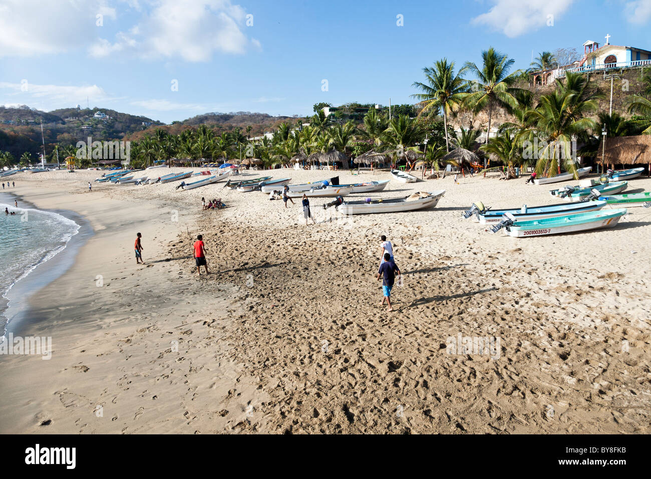 Messicano adolescenti ragazzi giocare pick up gioco di calcio sulla spiaggia orlata di palme con spiaggiata barche da pesca Puerto Angel dello Stato di Oaxaca Messico Foto Stock