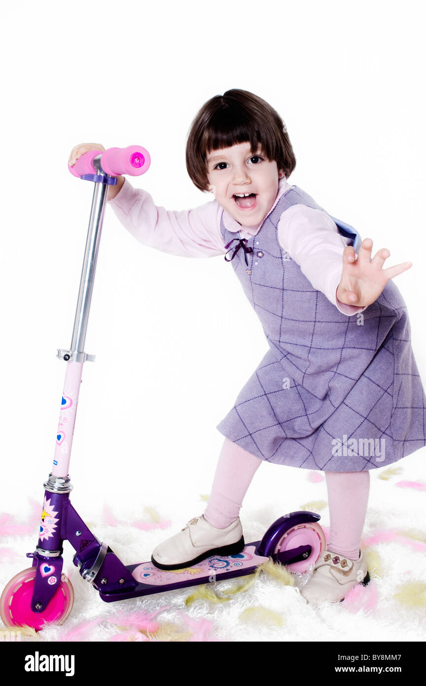 Bambina correre in giro per il suo scooter Foto Stock