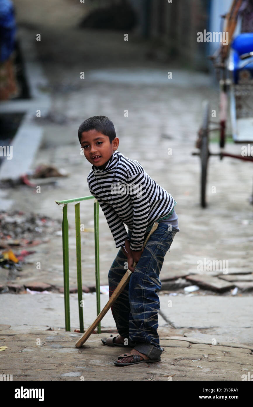 Kid a giocare a cricket in una piccola strada del Sud Bangaladesh Foto Stock