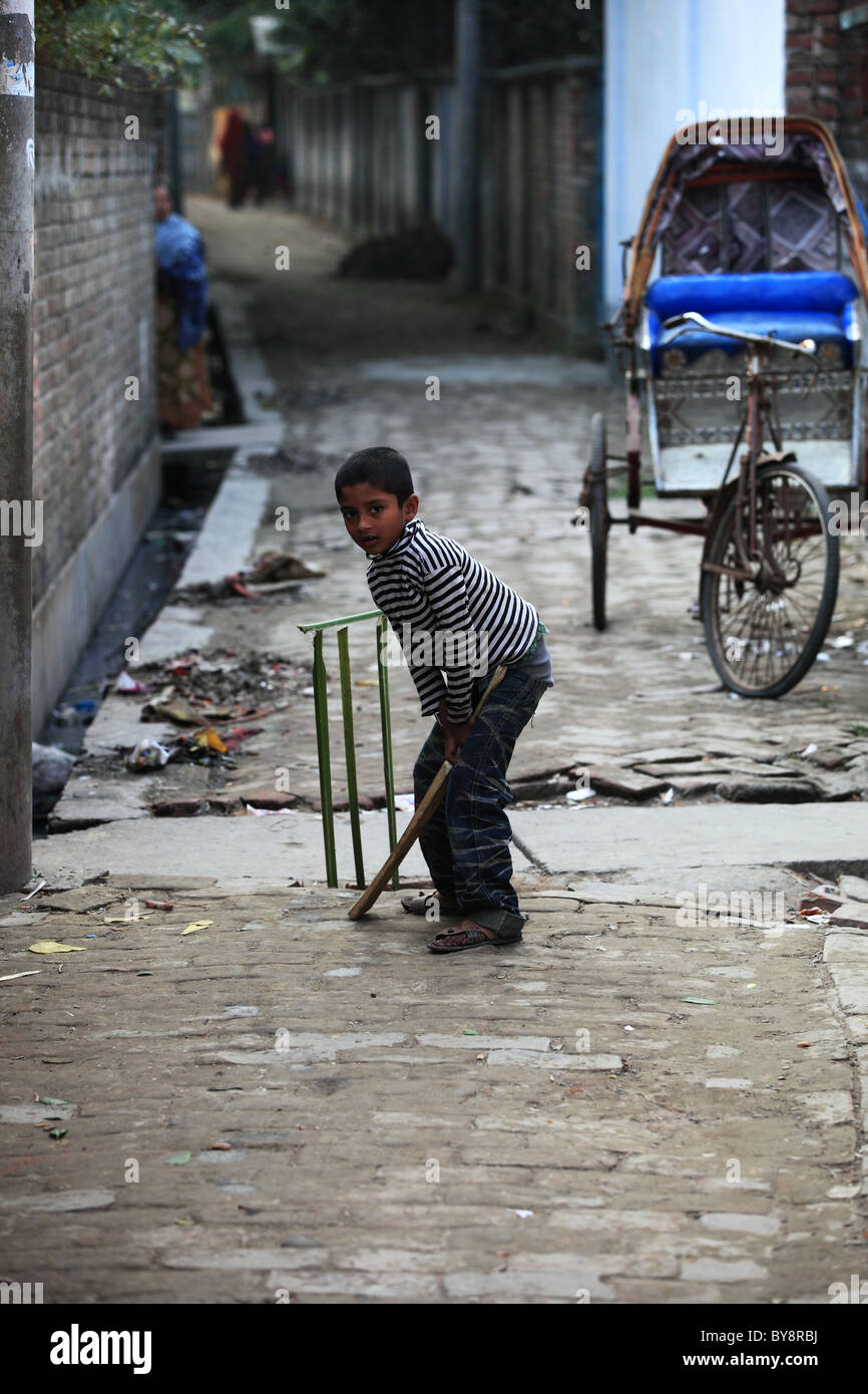 Kid a giocare a cricket in una piccola strada del Sud Bangaladesh Foto Stock