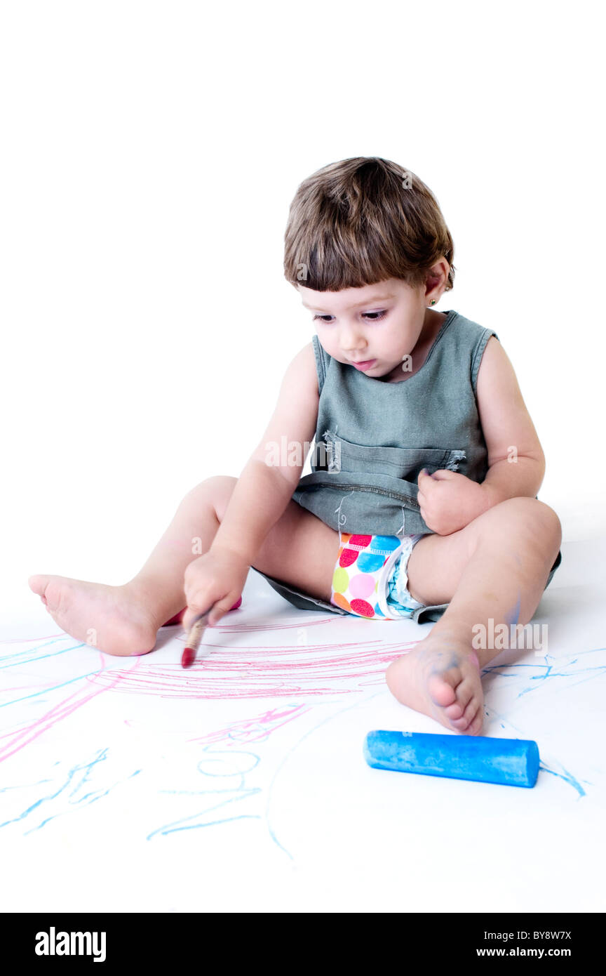 Ragazza seduta sul pavimento e pittura con gesso e plastidecors sul terreno Foto Stock