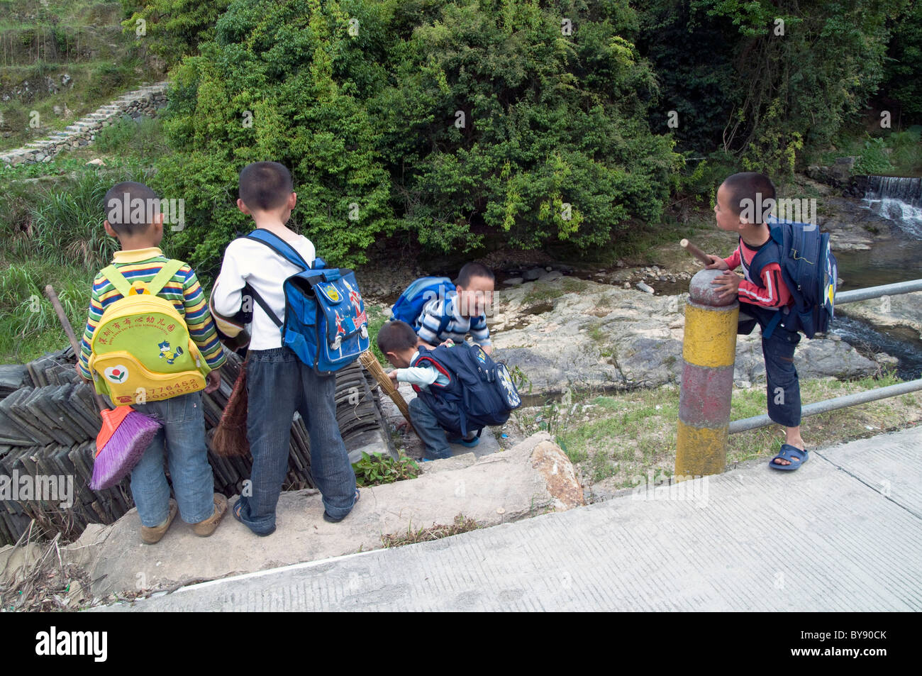 In Cina i figli dei lavoratori migranti dalla campagna andare a scuola a piedi in provincia di Yunnan Foto Stock