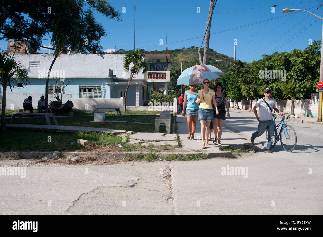 Street View di Holguin a Cuba con donne con ombrellone e ragazzo con una  bici Foto stock - Alamy