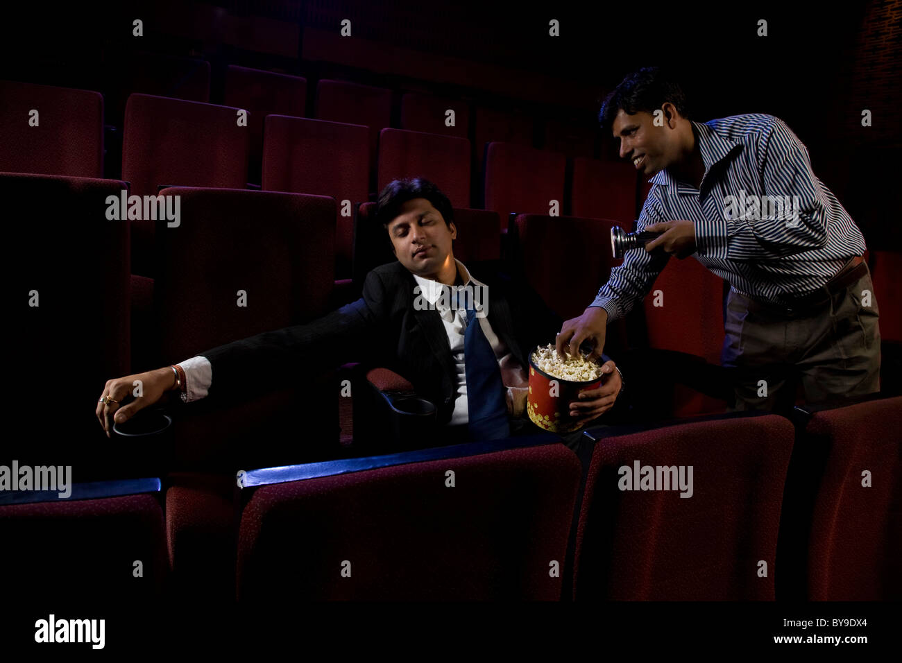 Sala cinema attendant tenendo il popcorn da un uomo del sonno Foto Stock