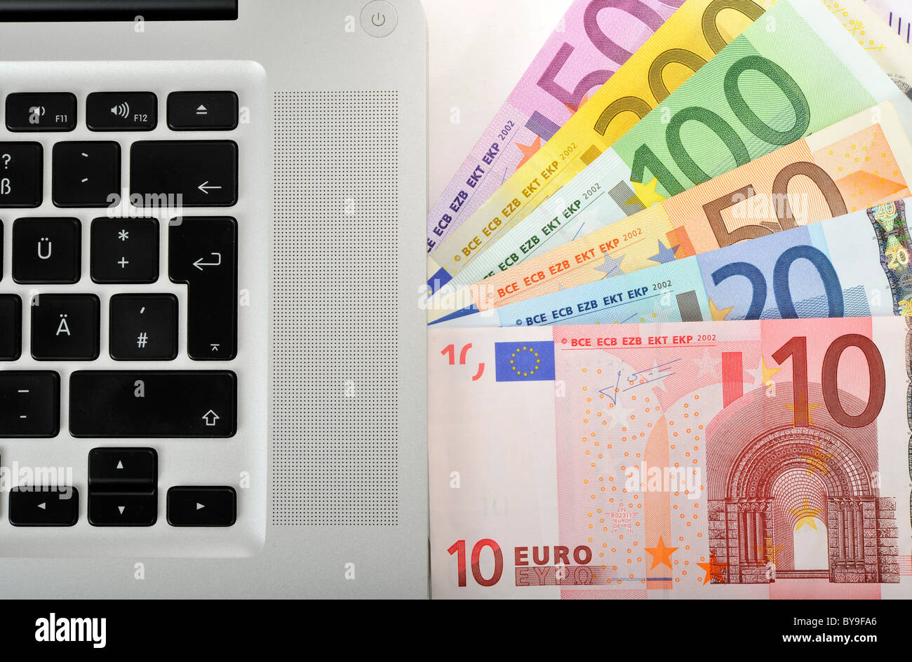 Fan di varie banconote in euro a fianco di un laptop, PC, immagine simbolica per internet business o lo shopping online Foto Stock