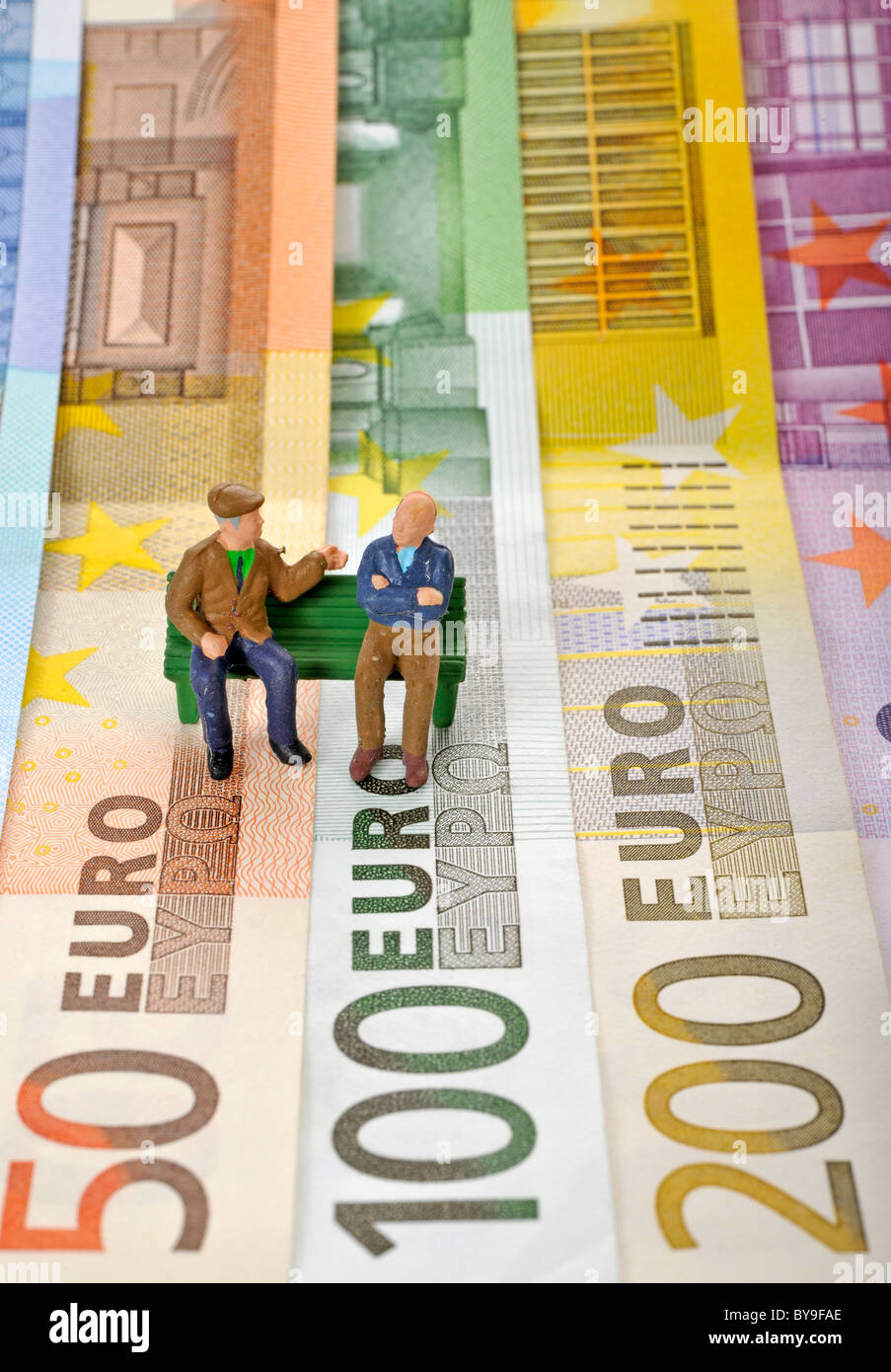 Varie banconote in euro con figure in miniatura di cittadini anziani su una panchina nel parco, immagine simbolica per la pensione o pensione di Foto Stock