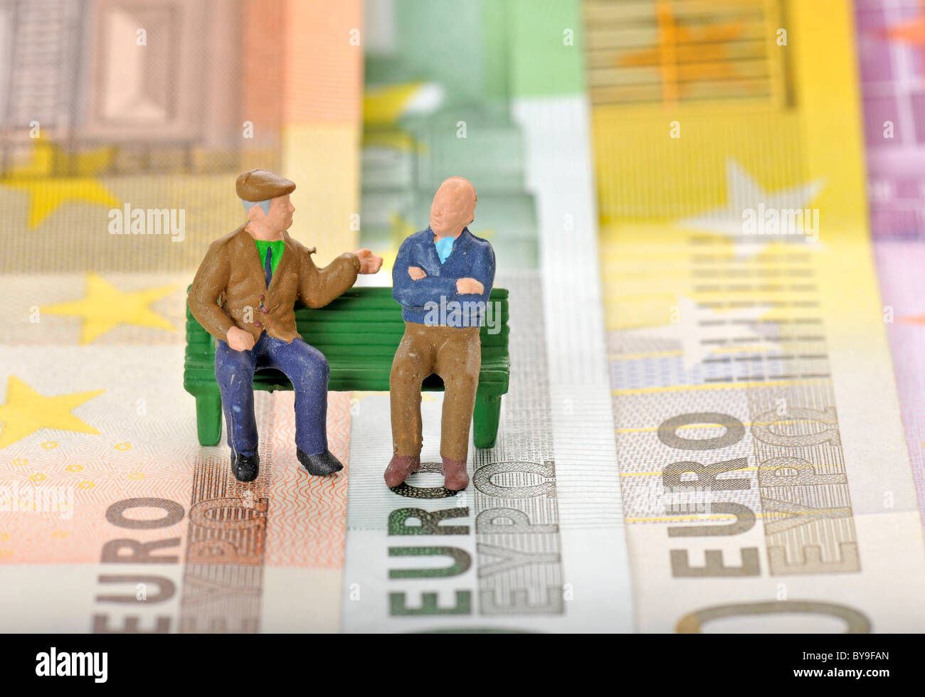 Varie banconote in euro con figure in miniatura di cittadini anziani su una panchina nel parco, immagine simbolica per la pensione o pensione di Foto Stock