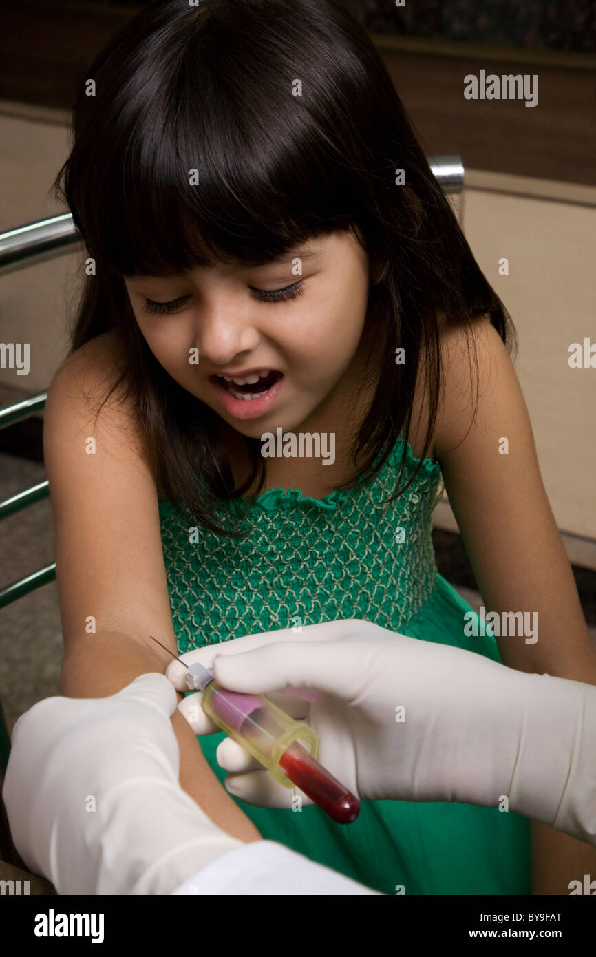 Medico di prendere un campione di sangue da una ragazza Foto Stock