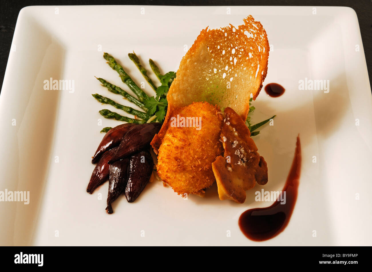 L anatra arrosto con fegato cotta in camicia uovo, gli asparagi selvatici e cipolla rossa confit servita su una piastra bianca, cibo, haute cuisine Foto Stock