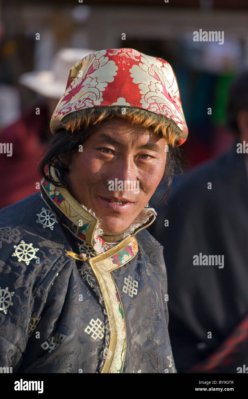 Il Tibetano uomo pellegrino in rosso di fantasia e cappello bianco in Barkhor Lhasa il Tibet. JMH4639 Foto Stock