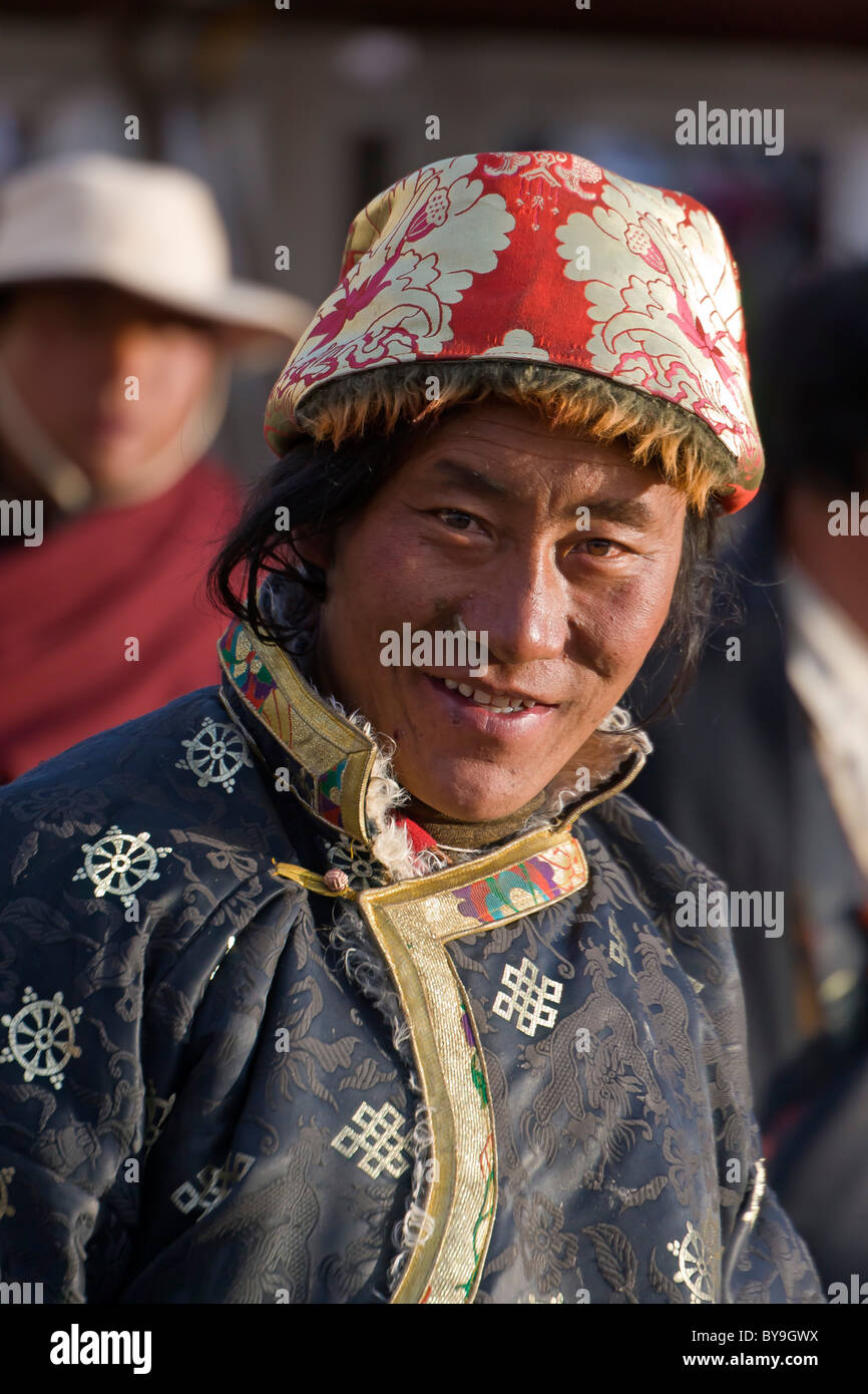 Il Tibetano uomo pellegrino in rosso di fantasia e cappello bianco in Barkhor Lhasa il Tibet. JMH4640 Foto Stock
