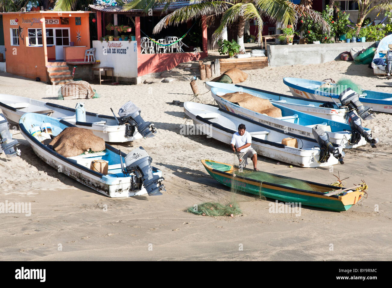 Spiaggiata barche da pesca nel pomeriggio su Puerto Angel beach messicano con lo spooling del pescatore il suo netto dello Stato di Oaxaca Messico Foto Stock