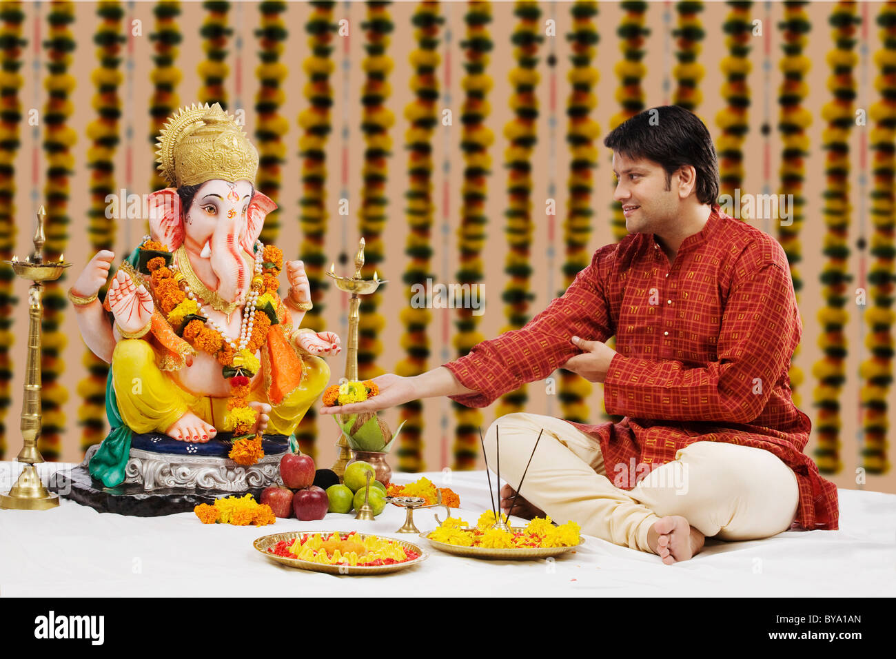 L'uomo offrendo fiori al Signore Ganesh Foto Stock