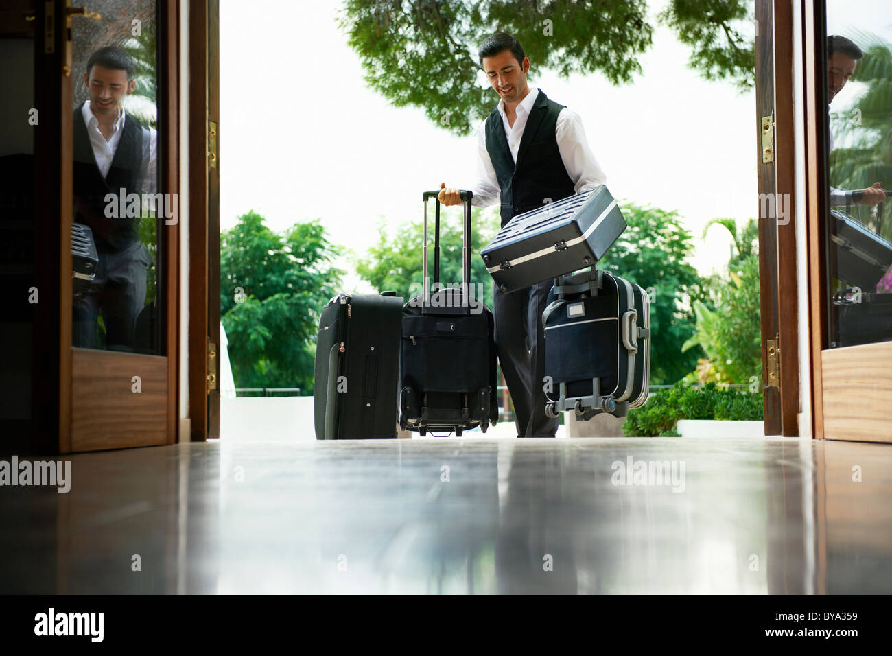 Uomo che porta le valigie in hotel Foto Stock