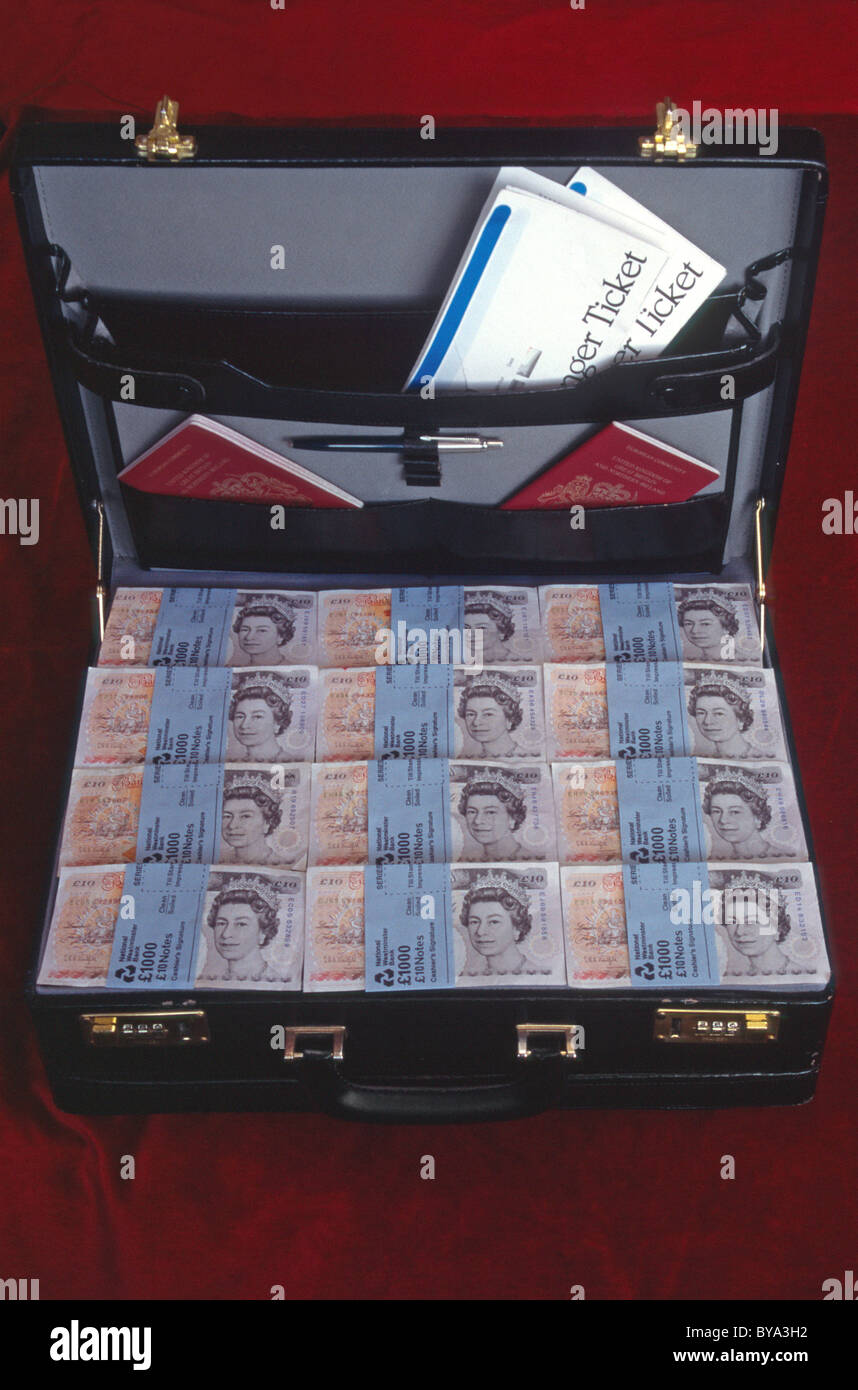 Valigetta piena di sterlina inglese in contanti con documenti di viaggio e due passaporti rossi del Regno Unito borgogna immagine riciclaggio di denaro Foto Stock