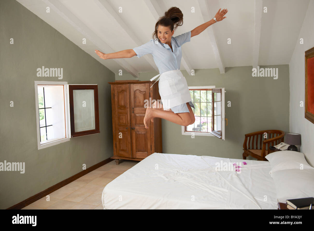 Hotel cameriera di saltare sul letto in camera Foto Stock