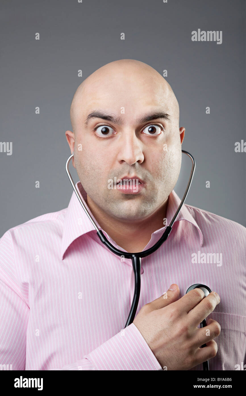 L'uomo utilizzando uno stetoscopio per controllare la sua frequenza cardiaca Foto Stock
