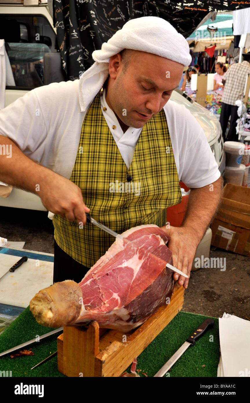 Venditore con prosciutto italiano Prosciuto o a un cavalletto di specialità sul mercato degli agricoltori, Roma, Lazio, l'Italia, Europa Foto Stock