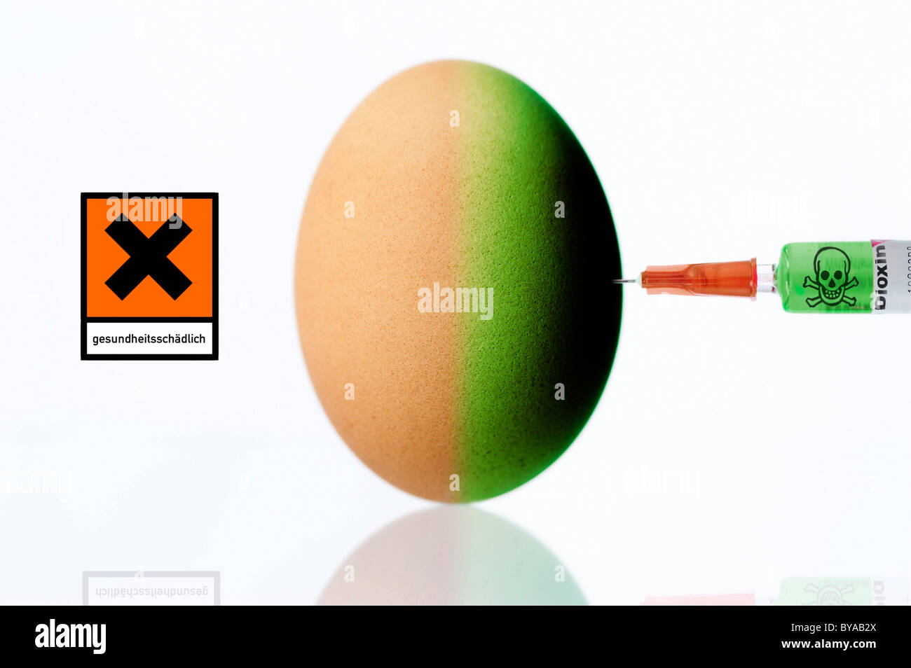 Un uovo di gallina che viene iniettata con la diossina in una siringa e un avvertimento per la salute segno, immagine simbolica per la contaminazione da diossina nei polli Foto Stock