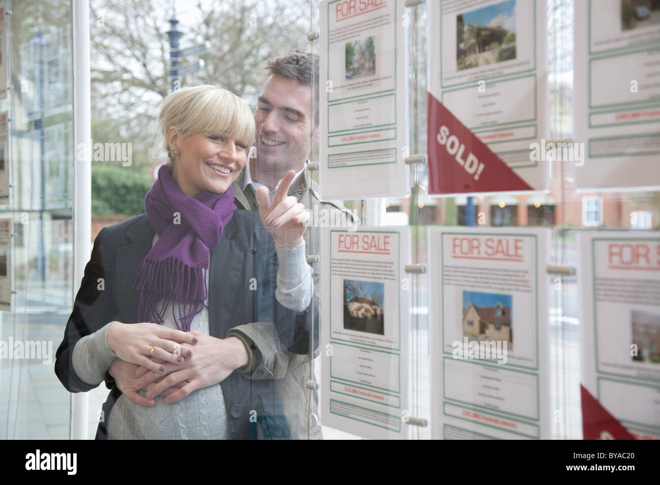 Giovane cercando in agenti immobiliari finestra Foto Stock