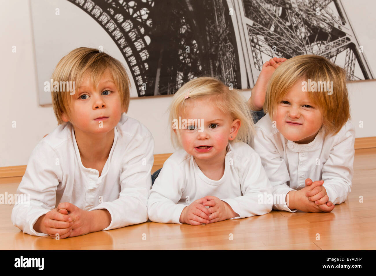 2 ragazzi di 7 e uno di 4 anni e una ragazza, 1,5 anni, sdraiato sul pavimento Foto Stock