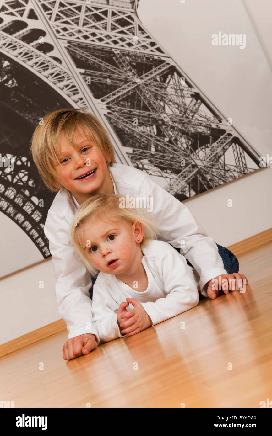 Il ragazzo, 7 anni, e la ragazza, 1,5 anni, sdraiato sul pavimento Foto Stock