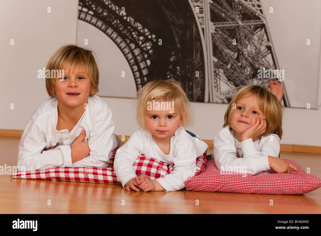 2 ragazzi di 7 e uno di 4 anni e una ragazza, 1,5 anni, sdraiato sul pavimento Foto Stock