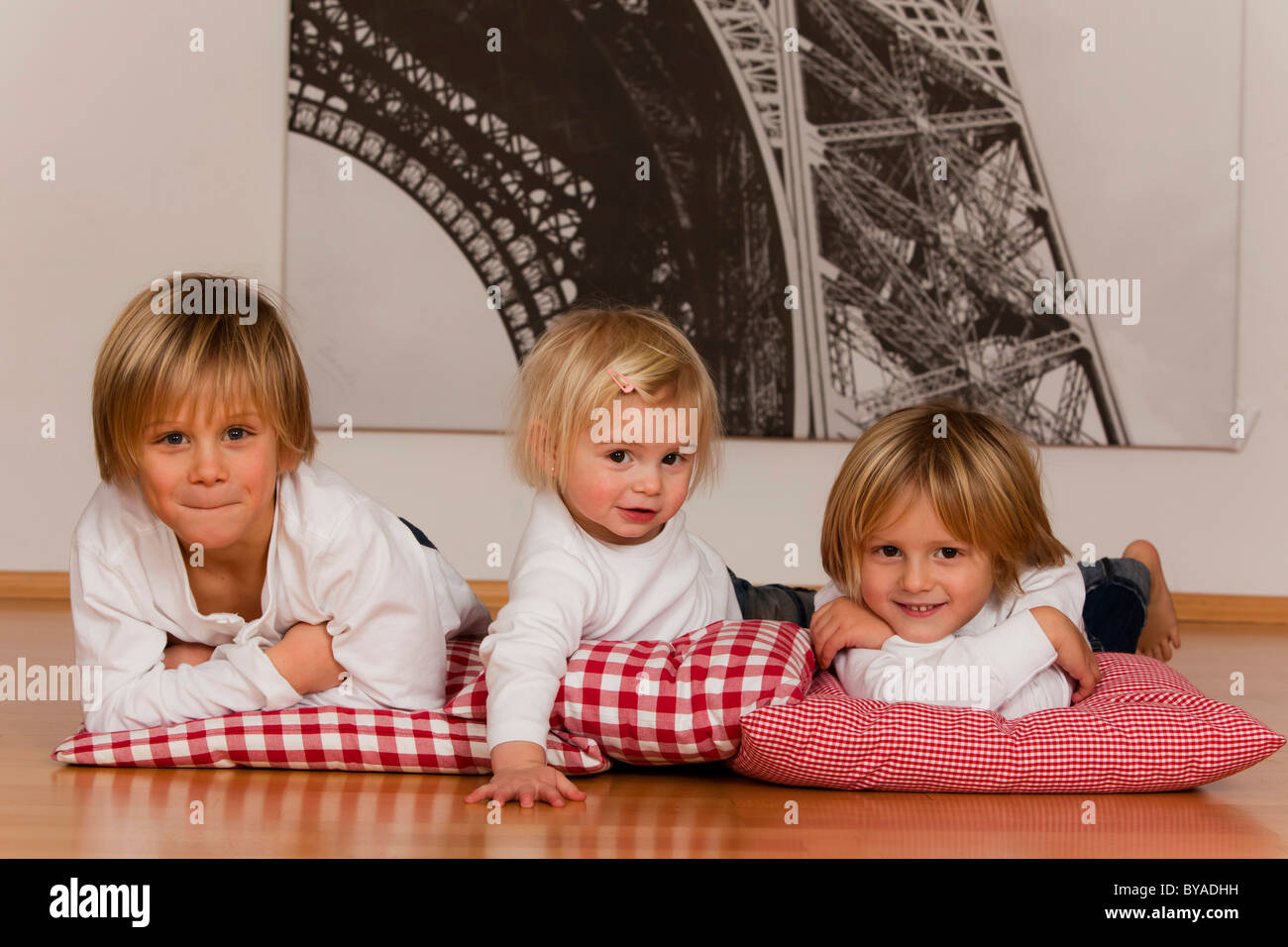 2 ragazzi di 7 e uno di 4 anni e una ragazza, 1,5 anni, sdraiato sul pavimento Foto Stock