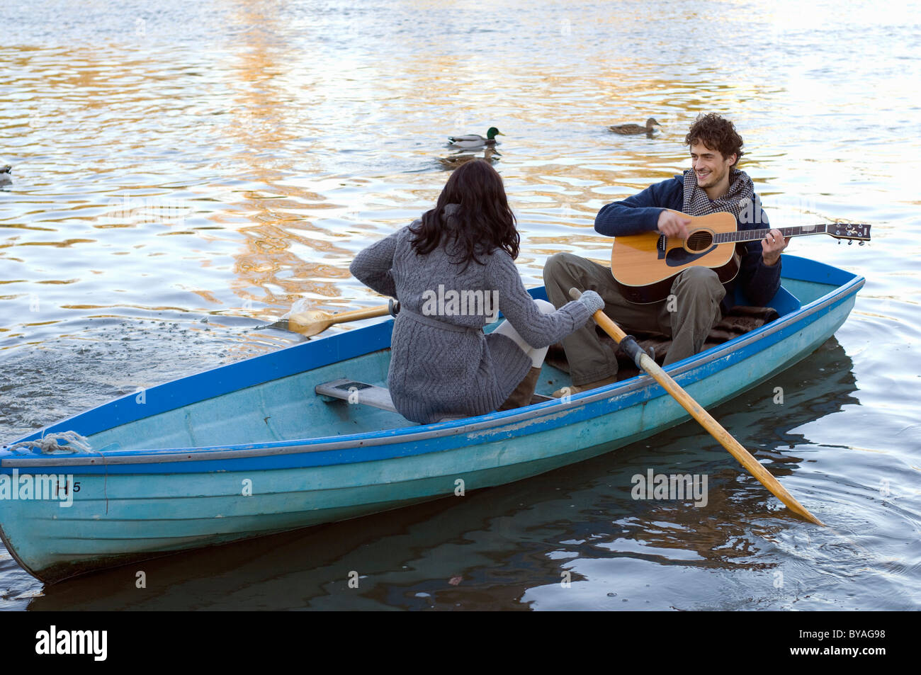 Uomo a suonare la chitarra in barca a remi Foto Stock