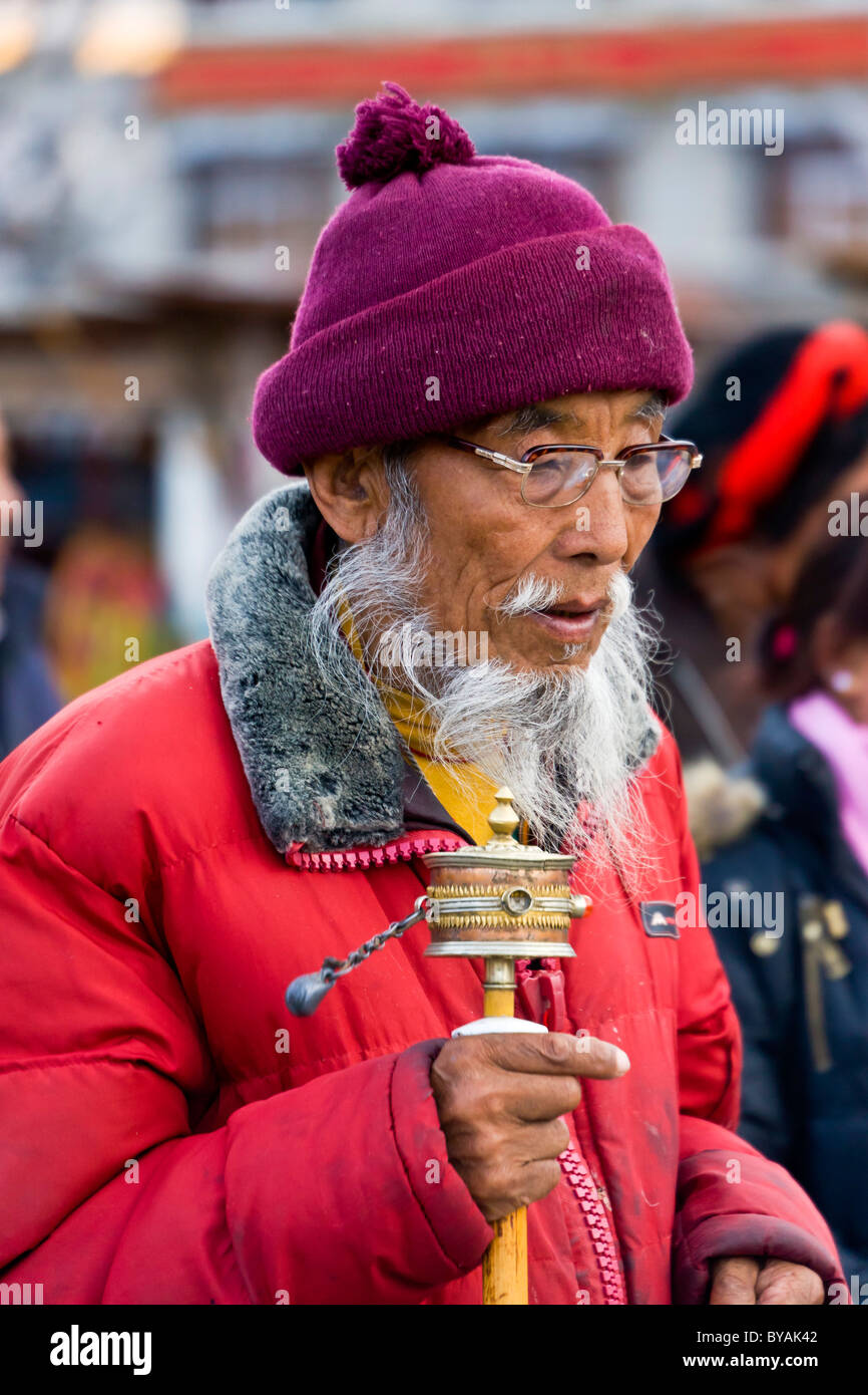 Il vecchio uomo tibetano pellegrino con la barba bianca e i baffi di filatura ruota di preghiera del Barkhor Lhasa il Tibet. JMH4695 Foto Stock