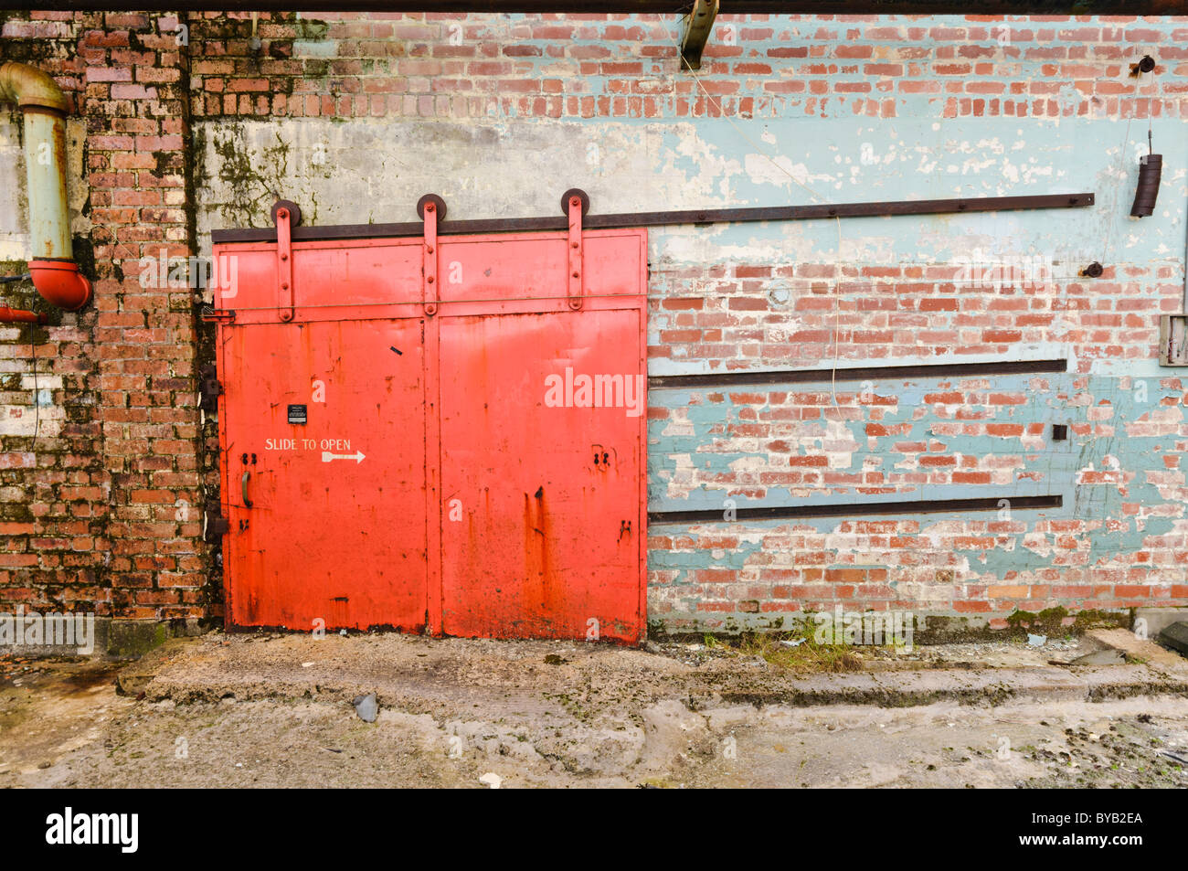 Vecchio, rosso porta scorrevole sul lato di una fabbrica/magazzino Foto Stock